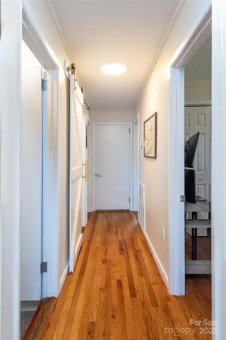 a view of a hallway with wooden floor and a bathroom