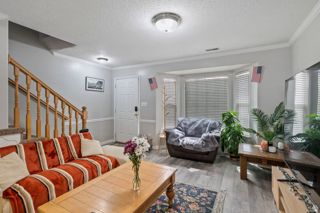 962 Independence Avenue Provo, UT 84604 - Photo 1 of 31 Living room featuring stairway, ornamental molding, a textured ceiling, and wood finished floors