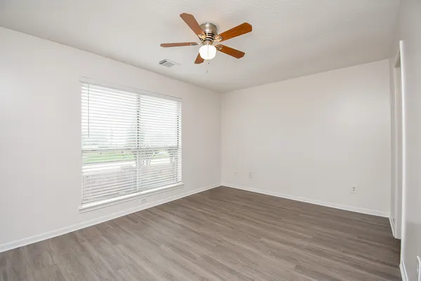 an empty room with wooden floor and windows