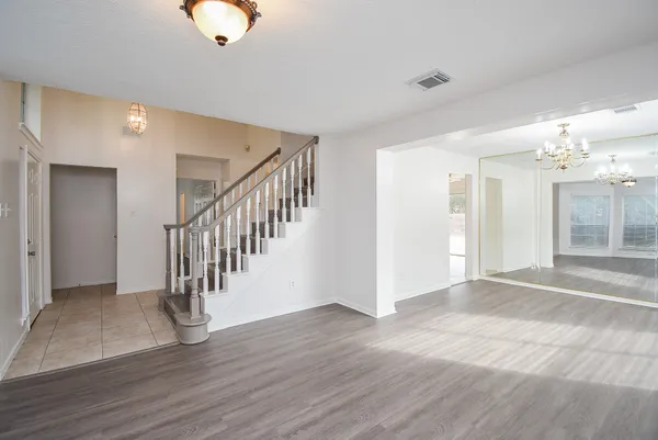 a view of an empty room with wooden floor and a chandelier