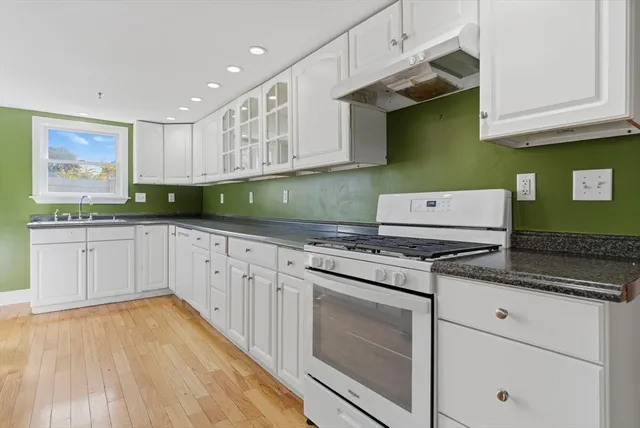 a kitchen with stainless steel appliances granite countertop a refrigerator a stove and a sink