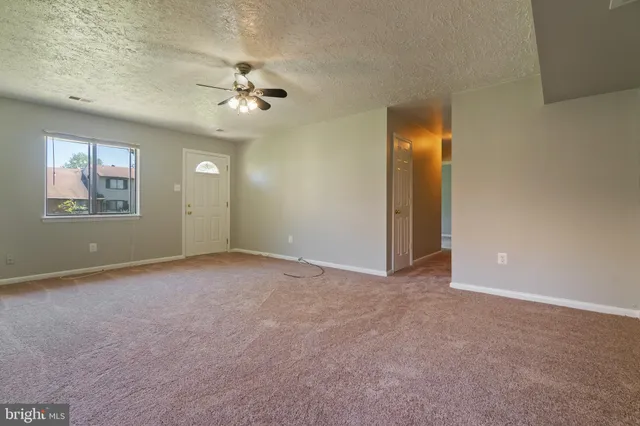an empty room with windows and fan