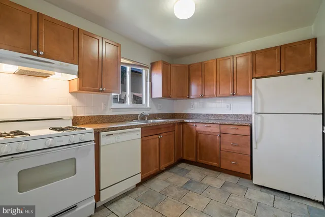a kitchen with granite countertop a refrigerator sink stove and cabinets