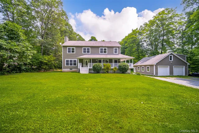 a front view of house with yard and trees in the background