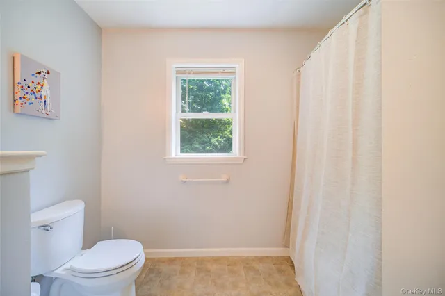 a view of a hallway with wooden floor and a bathroom