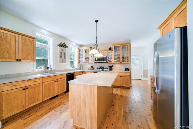 a large kitchen with kitchen island a large counter top space a sink stainless steel appliances and cabinets
