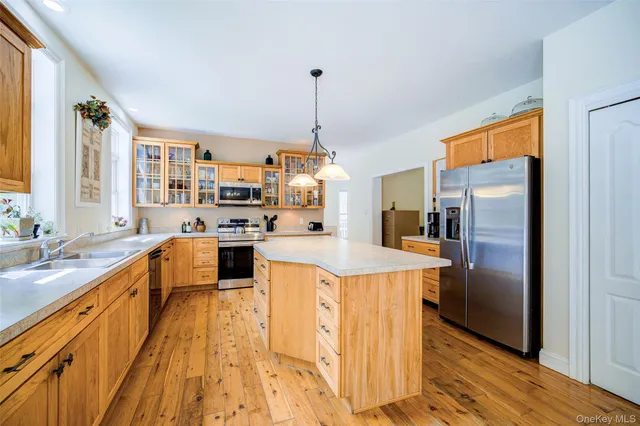 a kitchen with stainless steel appliances granite countertop a refrigerator a sink dishwasher a stove and a dining table with wooden floor