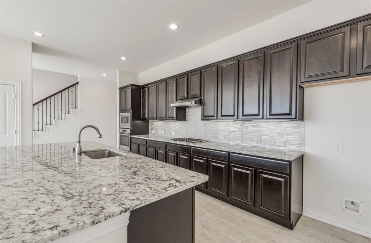 3223 Harmony Creek Lane Spring, TX 77386 - Photo 13 of 34 a kitchen with stainless steel appliances granite countertop a sink dishwasher stove and refrigerator with wooden cabinets