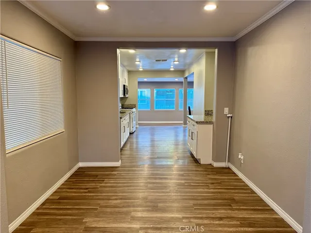 a view of a hallway with wooden floor and a bathroom