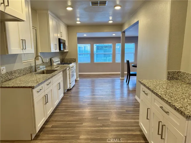 a large kitchen with stainless steel appliances a large counter top and a wooden floors