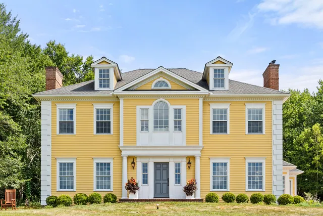 a front view of a residential apartment building with windows and yard