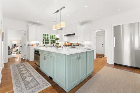 a kitchen with a stove a sink a refrigerator and windows