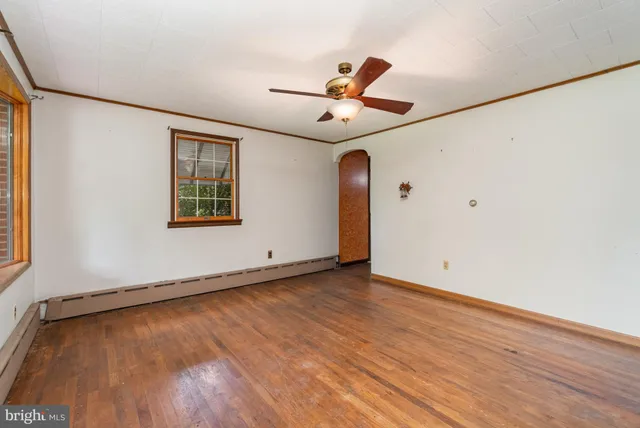 an empty room with wooden floor ceiling fan and windows