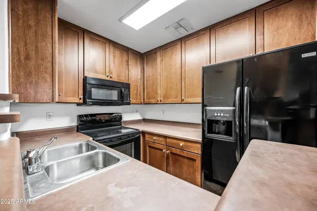 a kitchen with granite countertop wooden cabinets a refrigerator and a sink