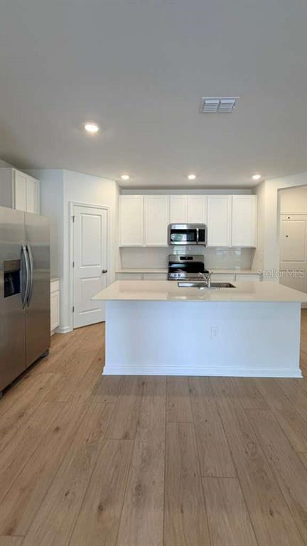 5174 Clay Whaley Road St. Cloud, FL 34772 - Photo 5 of 25 a kitchen with granite countertop a stove a sink dishwasher a refrigerator and white cabinets with wooden floor