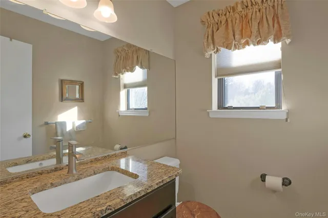 a bathroom with a granite countertop sink a mirror and a bathtub