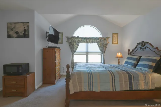 a bedroom with a bed a mirror on dresser and a window