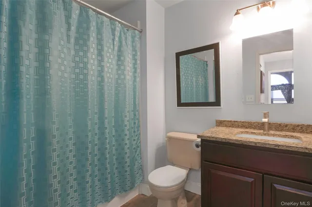 a bathroom with a granite countertop toilet and a sink