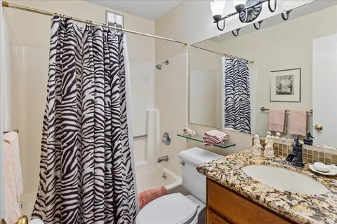 a bathroom with a granite countertop sink a toilet and a mirror
