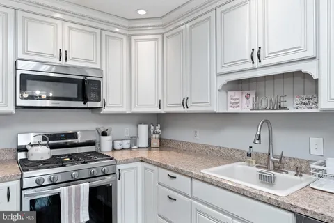 a kitchen with granite countertop white cabinets and stainless steel appliances