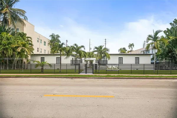 a view of a house in a big yard with palm trees