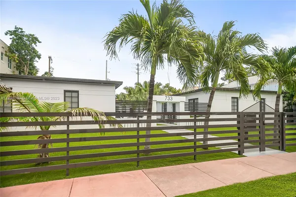 a front view of a house with a garden and tree