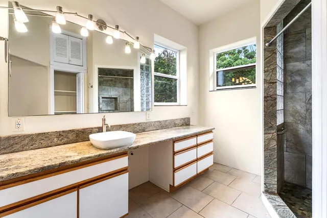 a bathroom with a granite countertop sink mirror and a shower