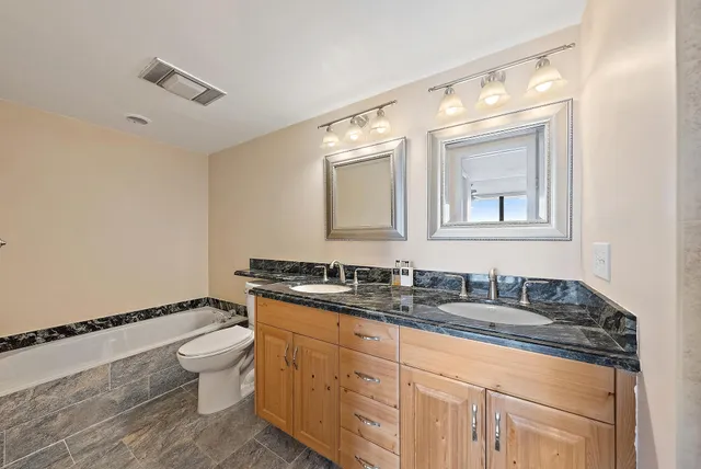 a bathroom with a granite countertop toilet sink and mirror