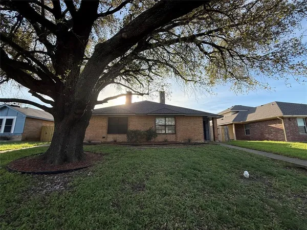a view of a yard in front of a house with a large tree