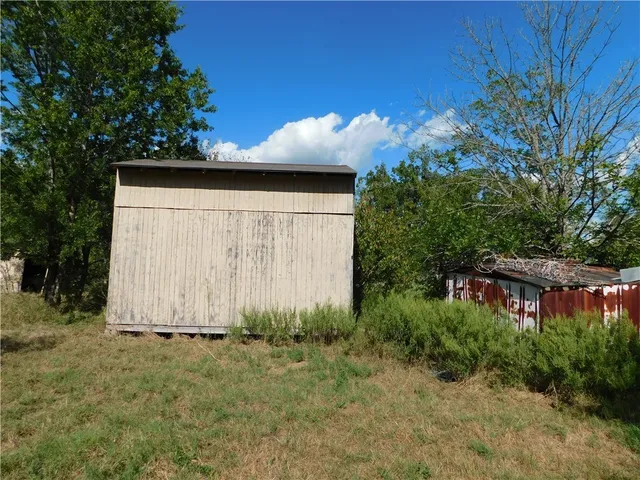 a view of a backyard with potted plants and large trees