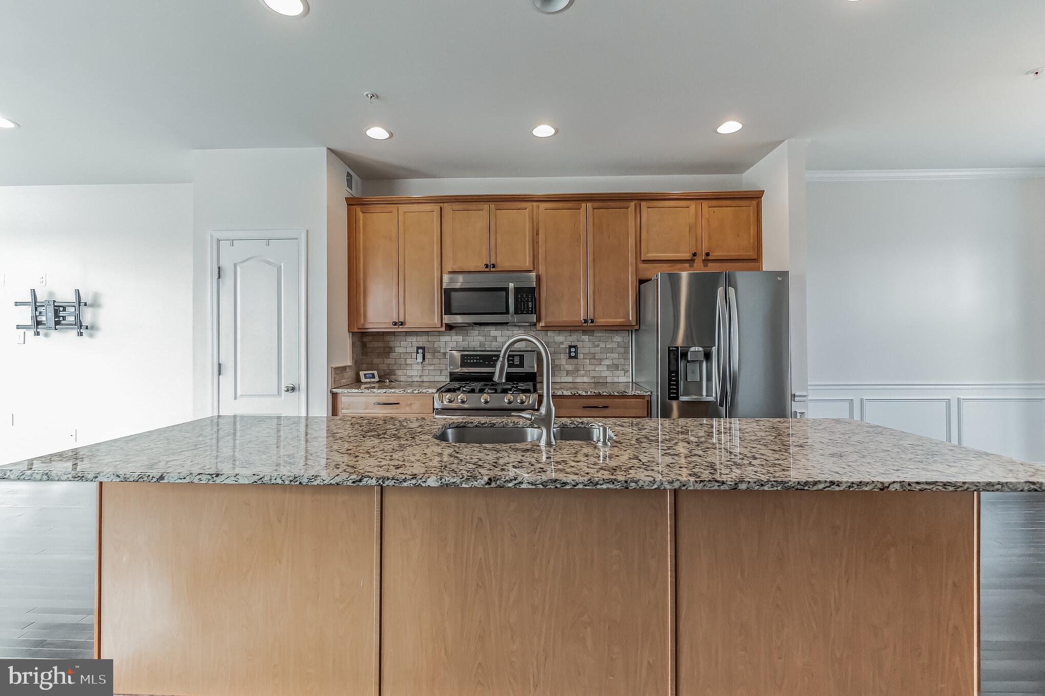 7652 Town View Drive Dundalk, MD 21222 - Photo 8 of 33 a kitchen with kitchen island granite countertop a refrigerator a stove top oven and large trees