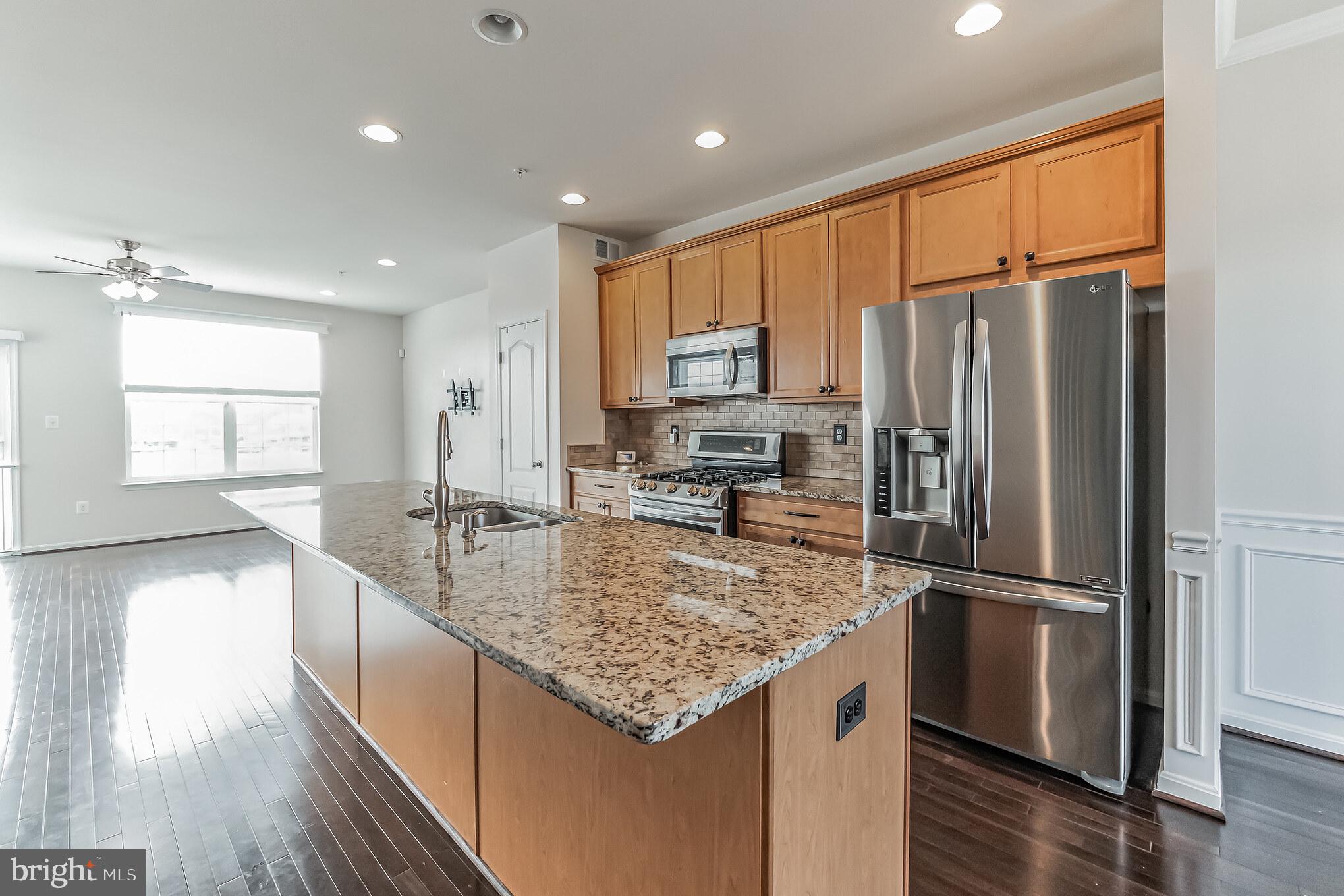 7652 Town View Drive Dundalk, MD 21222 - Photo 9 of 33 a kitchen with kitchen island granite countertop a refrigerator a sink and wooden floors