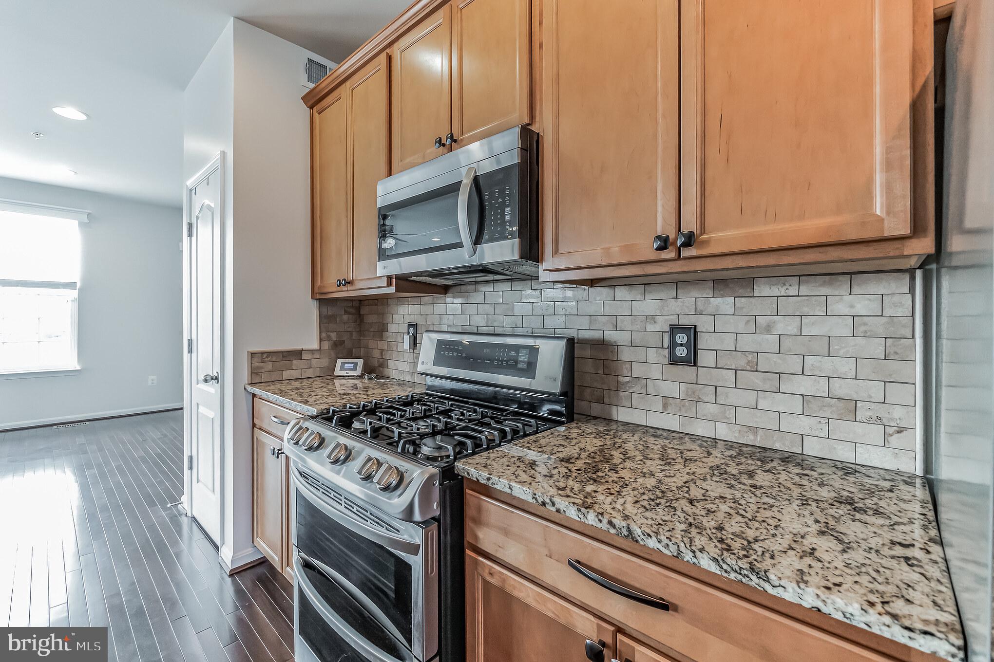7652 Town View Drive Dundalk, MD 21222 - Photo 10 of 33 a kitchen with stainless steel appliances granite countertop a stove a microwave and a sink