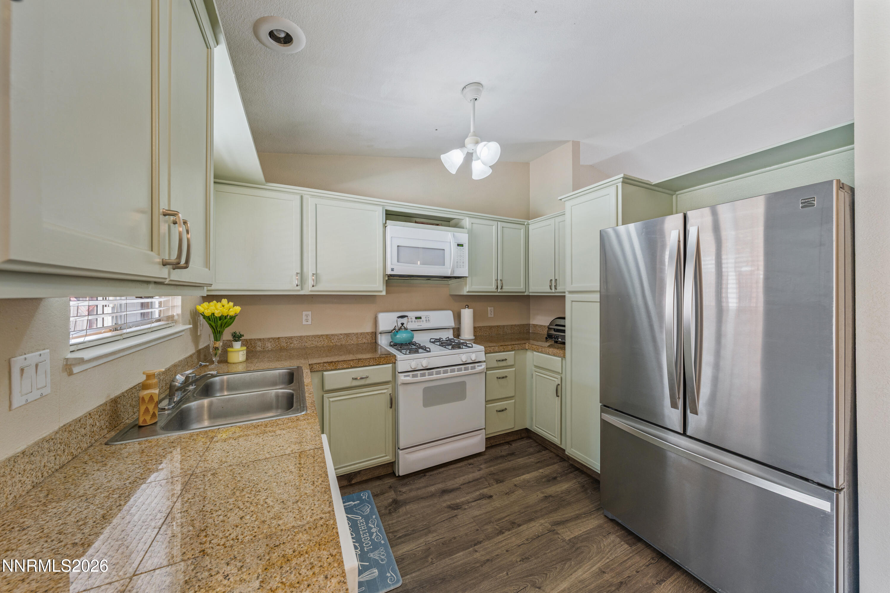 6370 Mono Court Sun Valley, NV 89433 - Photo 4 of 22 a kitchen with a refrigerator a white cabinets and wooden floor