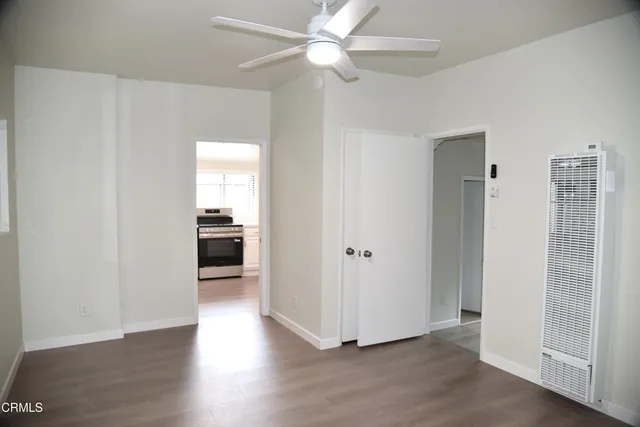 a view of a hallway with wooden floor and a ceiling fan