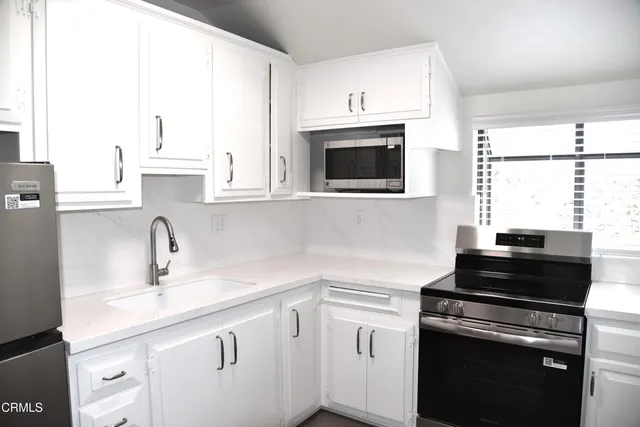 a kitchen with cabinets stainless steel appliances a sink and a window
