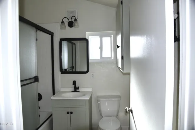 a bathroom with a toilet sink a mirror and vanity