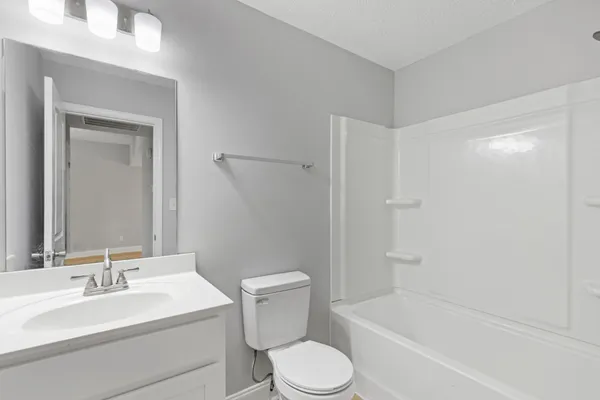 a bathroom with a toilet a sink a mirror a bathtub and vanity