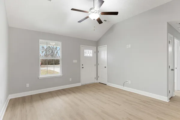 a view of empty room with wooden floor and fan