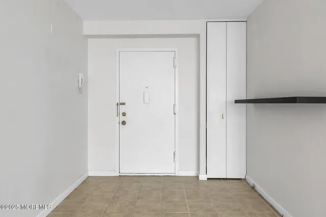 a view of an empty room with closet and a bathroom