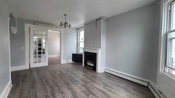 an empty room with wooden floor fireplace and windows