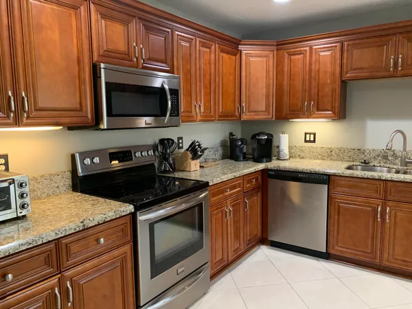 a kitchen with granite countertop stainless steel appliances a stove a sink and a microwave