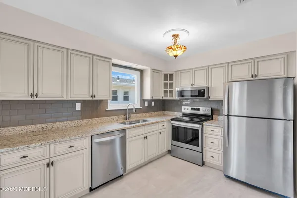 a kitchen with stainless steel appliances granite countertop a refrigerator a stove a sink dishwasher and white cabinets with wooden floor