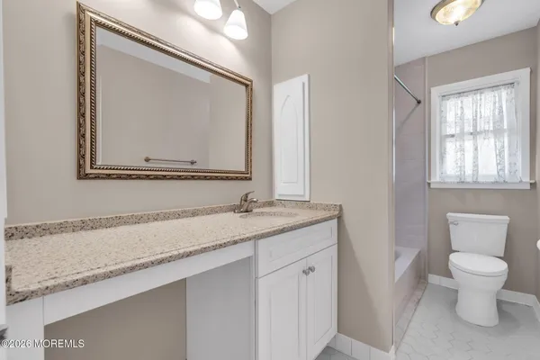 a bathroom with a granite countertop sink a toilet and a mirror