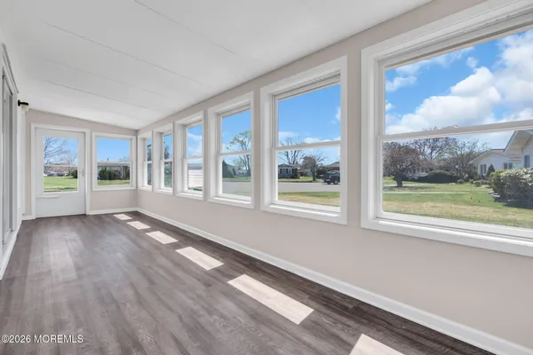 a view of an empty room with a window and wooden floor