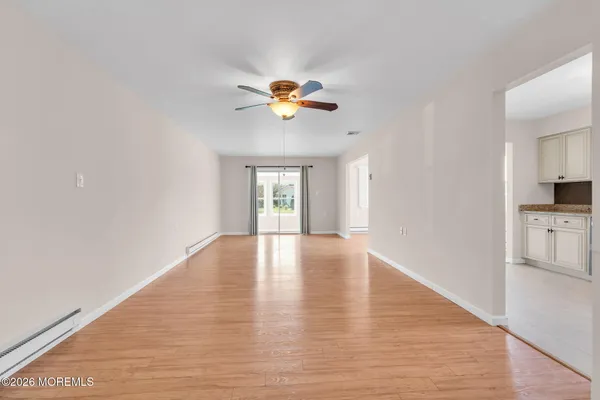 a view of empty room with wooden floor and fan