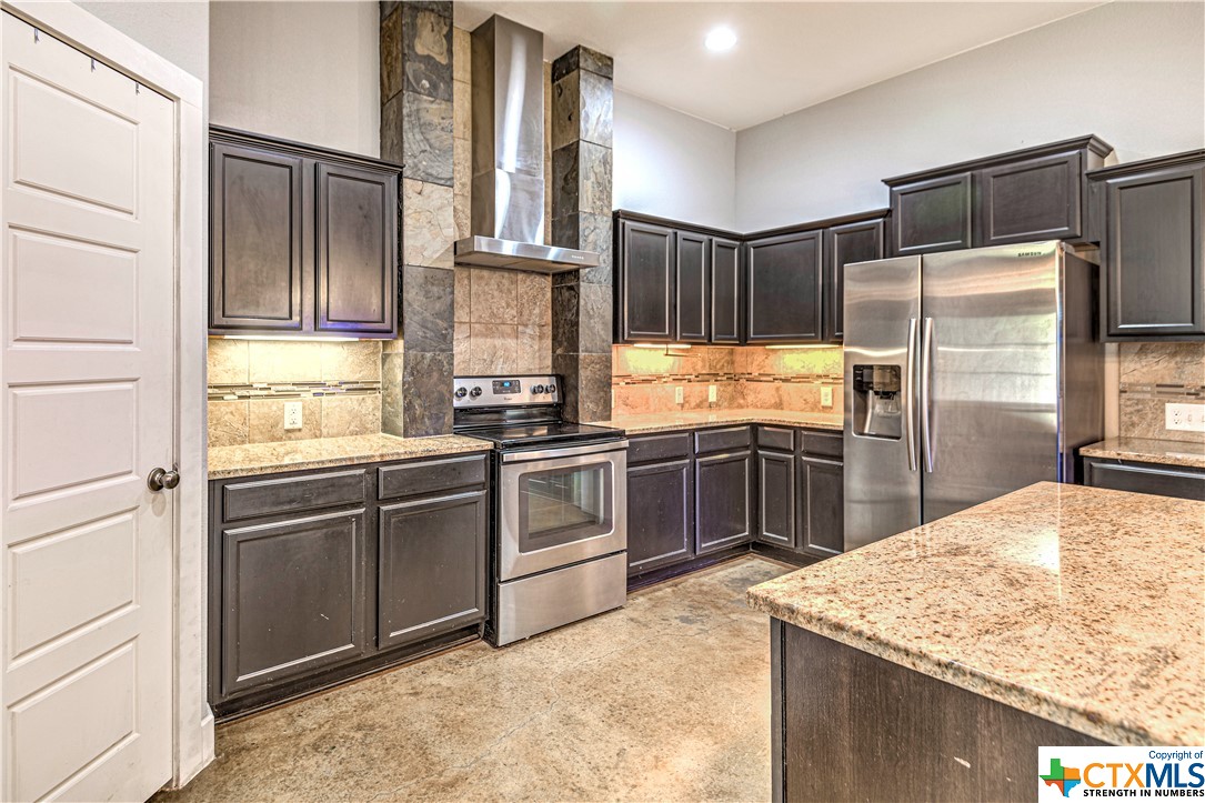 a kitchen with kitchen island granite countertop a refrigerator stove and oven