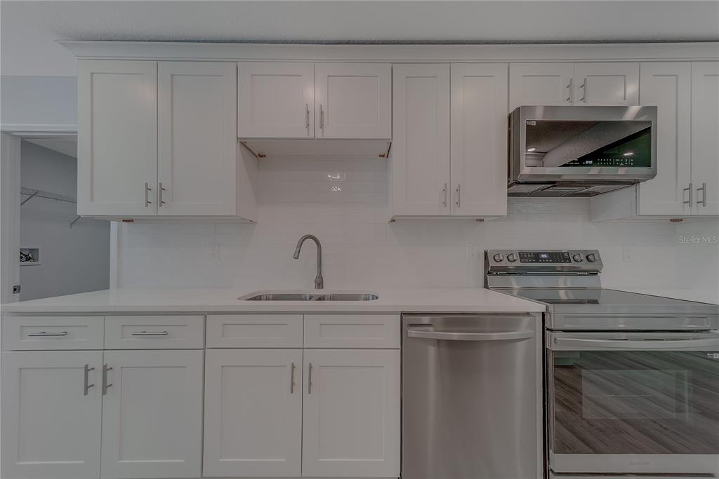 1152 Jackmar Road Dunedin, FL 34698 - Photo 18 of 60 a kitchen with white cabinets and stainless steel appliances