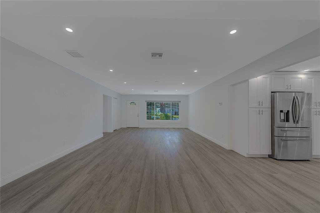 1152 Jackmar Road Dunedin, FL 34698 - Photo 10 of 60 a view of empty room with wooden floor and kitchen