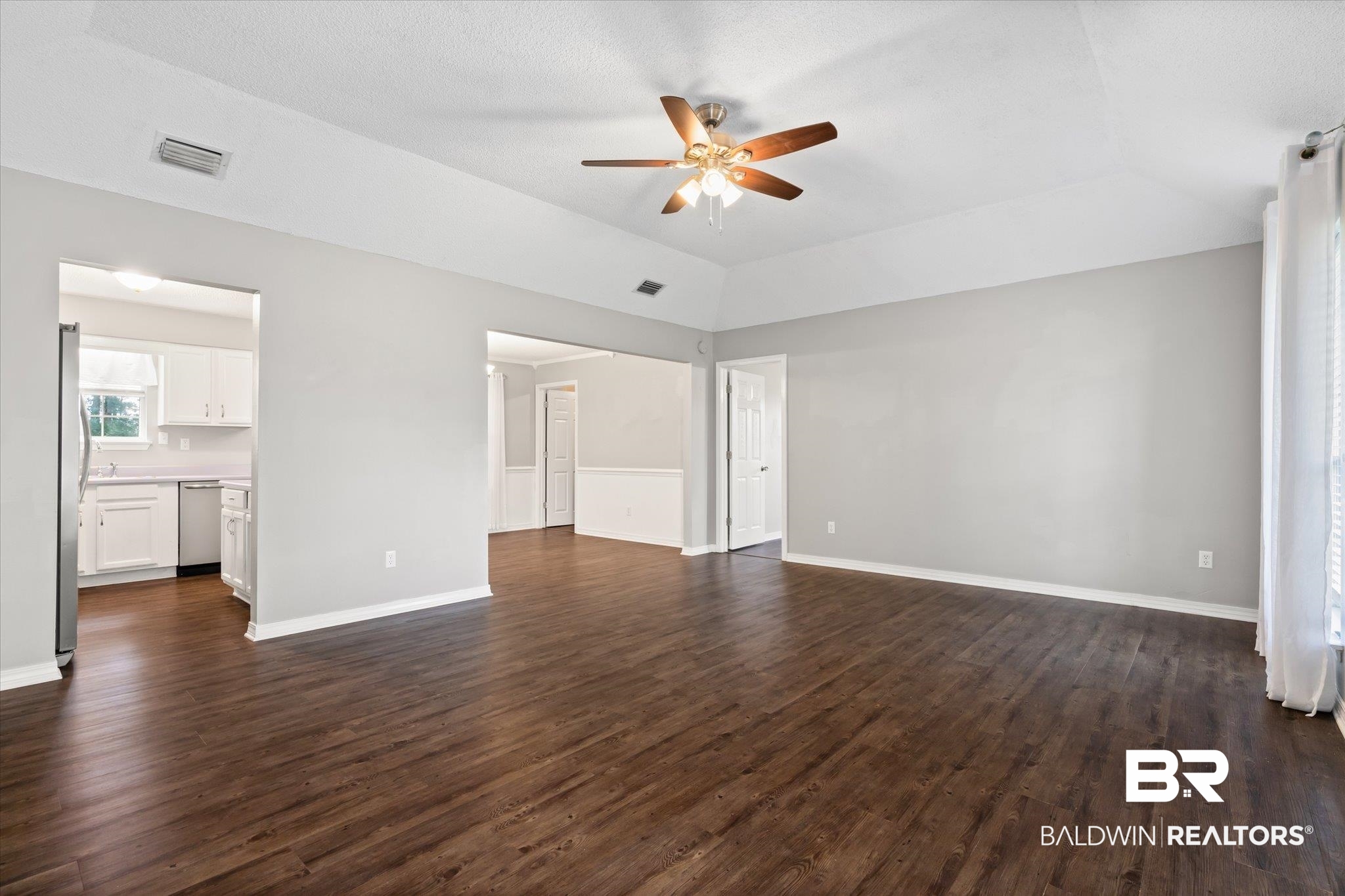16216 Pointer Drive Foley, AL 36535 - Photo 6 of 21 Spacious living area featuring wood-finish flooring, light gray wall paint, and a white tray ceiling with a ceiling fan